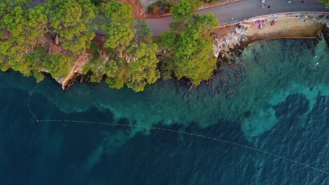 Aerial view of Beach Lanterna featuring rocky shores, pine trees, and clear turquoise waters along the coast of Stari Grad, Croatia.