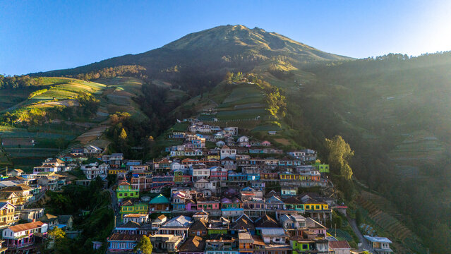 Aerial view of Nepal Van Java featuring colorful houses nestled on a terraced mountain slope under golden hour light in Kecamatan Kaliangkrik, Jawa Tengah, Indonesia.