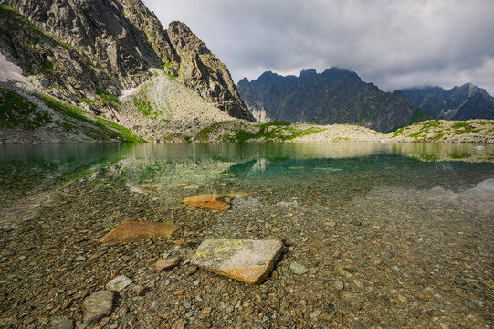 View of Litvorove pleso with its crystal clear water reflecting the surrounding high peaks of the High Tatras mountains under a cloudy sky in Tatranska Javorina, Presovsky kraj, Slovakia.