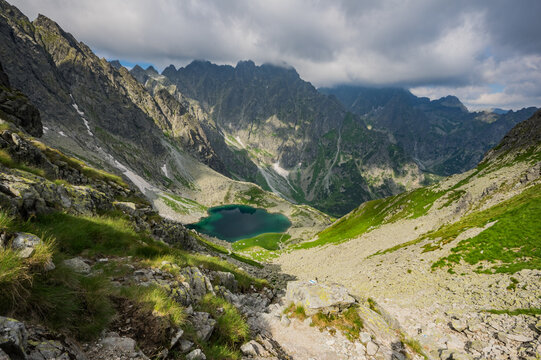 View of Litvorove pleso surrounded by dramatic rocky mountain peaks and lush green slopes in the High Tatras, Tatranska Javorina, Presovsky kraj, Slovakia.