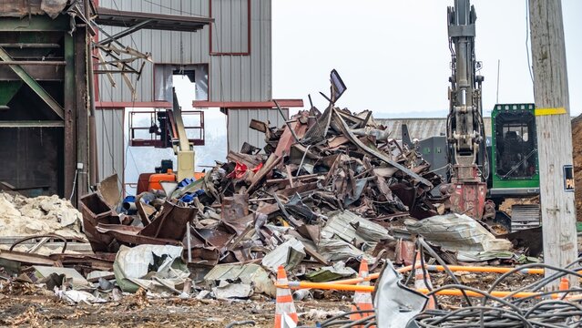 View of a demolition site with a large pile of scrap metal and heavy machinery in the USA.