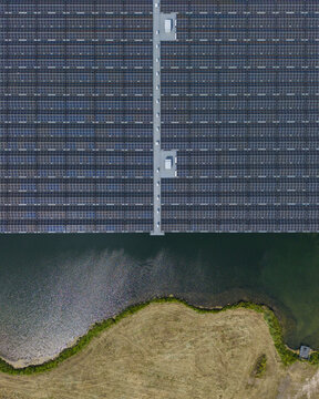 Aerial view of De Kolk floating solar park with rows of photovoltaic panels on water surface near grassy banks in Hattemerbroek, Gelderland, Netherlands.