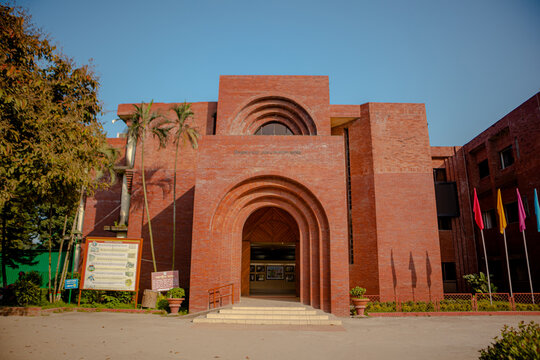 Sonargaon, Bangladesh - 19 November 2025: View of the Bangladesh Folk Art and Crafts Museum, a striking red brick building with arched entrances and palm trees under a clear blue sky.