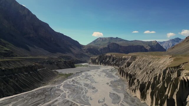 Aerial view of the rugged Spiti river valley with steep eroded cliffs and braided river channels under a clear blue sky in Lahaul and Spiti, Himachal Pradesh, India.