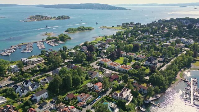 Aerial view of Bygdoy peninsula featuring lush greenery, residential houses, and a marina with boats along the coastline in Oslo, Oslo, Norway.