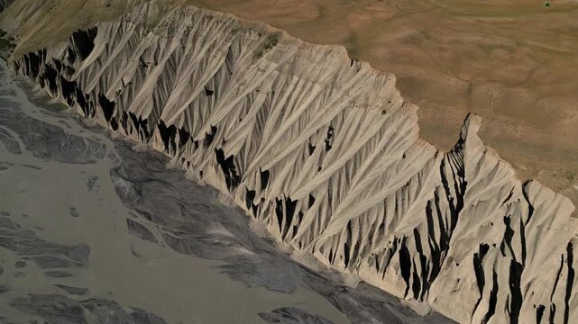 Aerial view of dramatic eroded mountain ridges and deep shadows in the rugged landscape of the Spiti Valley, Lahaul and Spiti, Himachal Pradesh, India.