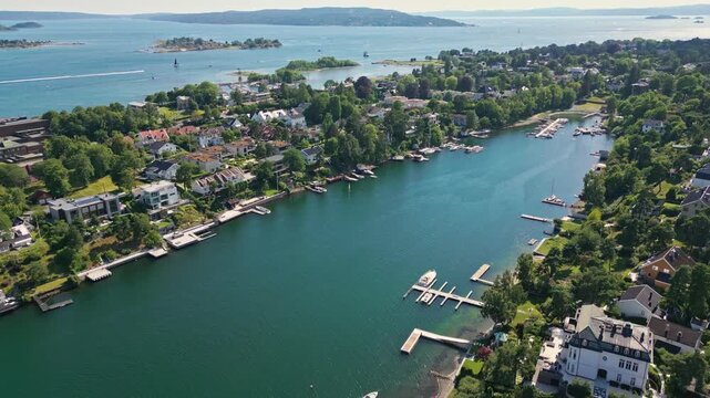 Aerial view of Bygdoy peninsula with lush greenery, residential houses, and small boat piers along the coastline in Oslo, Oslo, Norway.