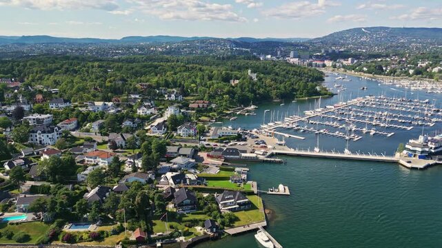 Aerial view of Bygdoy peninsula featuring a large marina with numerous boats, surrounded by lush green residential areas and the coastline of Oslo, Oslo, Norway.