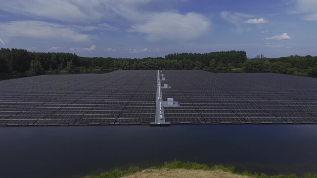 Aerial view of the floating solar farm at De Kolk, featuring rows of solar panels on the water surface surrounded by lush trees in Hattemerbroek, Gelderland, Netherlands.