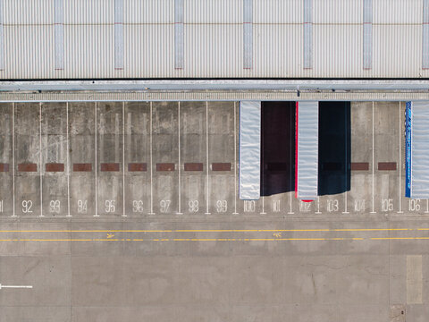 Aerial view of a commercial distribution centre loading bay with numbered parking spots and parked semi-trailers at Magna Park, England, United Kingdom.