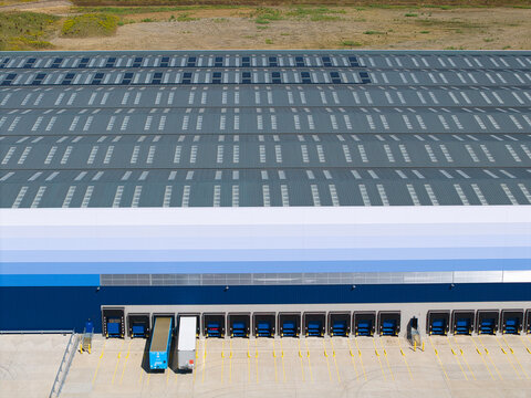 Aerial view of commercial distribution centre with large warehouse rooftops, loading bays, and parked HGV trailers in Magna Park, England, United Kingdom.