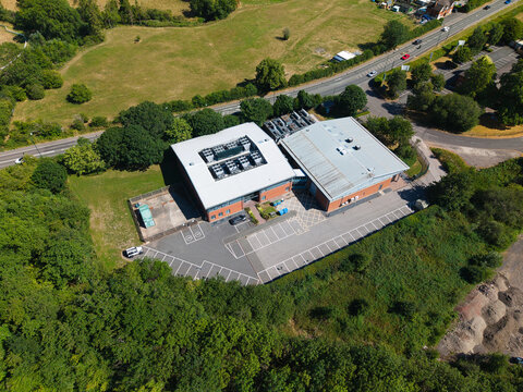 Aerial view of the Six Degrees Data Centre featuring industrial HVAC cooling ventilation systems on the roof, adjacent parking lot, and surrounding greenery in Studley, England, United Kingdom.