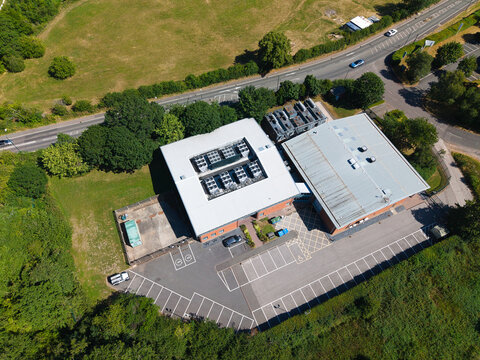 Aerial view of Six Degrees Data Centre featuring rooftop HVAC cooling ventilation units, a parking lot, and surrounding greenery in Studley, England, United Kingdom.