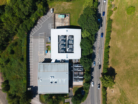 Aerial view of Six Degrees Data Centre featuring rooftop HVAC cooling ventilation systems, adjacent parking lot, and surrounding greenery in Studley, England, United Kingdom.
