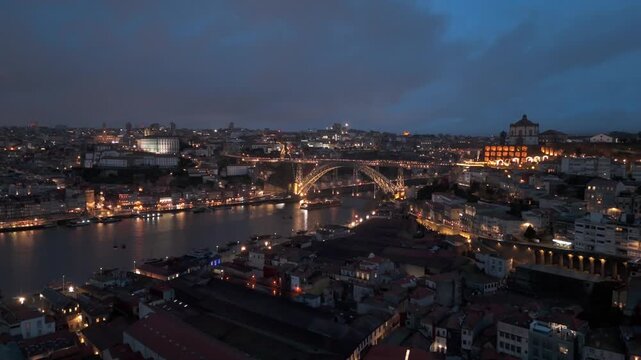 Aerial view of the illuminated Dom Luis I Bridge spanning the Douro River with city lights reflecting on the water in Porto, Porto District, Portugal.