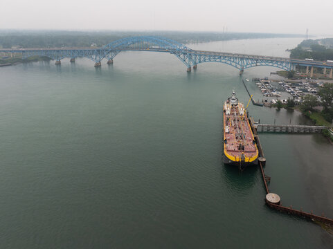 Buffalo, United States - 15 July 2026: Aerial view of Vane Brothers tugboat and barge refueling on the Niagara River with the South Grand Island Bridge under a hazy sky.