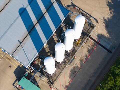 Aerial view of Gasrec Bio-LNG storage tanks at the DIRFT facility, with large white cylindrical containers next to a warehouse building in Kilsby, England, United Kingdom.