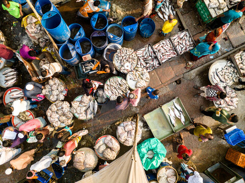 Dhaka, Bangladesh - 20 February 2026: Aerial view of the bustling Hazaribag fish market with vendors and customers surrounded by baskets of fresh fish and blue storage barrels.