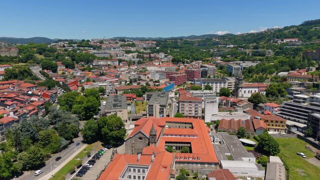 Aerial view of the Church of Saint Francis surrounded by historic rooftops, lush green trees, and urban streets in Guimaraes, Braga, Portugal.