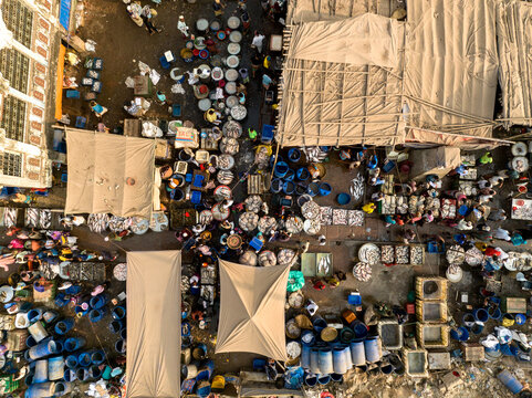 Dhaka, Dhaka Division, Bangladesh - 20 February 2026: Aerial view of Hazaribag fish market with numerous blue barrels, fresh fish, and people navigating between stalls under fabric canopies.
