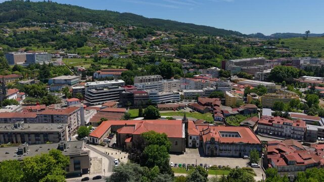 Aerial view of the Church of Saint Francis surrounded by historic buildings, red-tiled rooftops, and lush green hills in Guimaraes, Braga, Portugal.