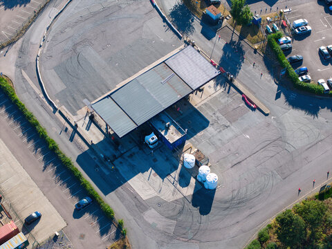 Aerial view of Rugby Truckstop with fuel pumps, parked trucks, and asphalt parking area in Rugby, England, United Kingdom.
