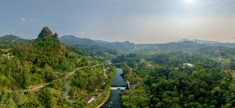 Aerial view of Wadaslintang Reservoir surrounded by lush green hills, tropical forest, and winding river paths in Wadaslintang, Central Java, Indonesia.