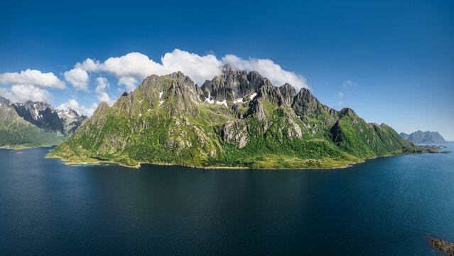 Aerial view of the dramatic Austnesfjorden with its lush green mountains and rocky peaks rising above the deep blue waters in Vagan, Nordland, Norway.
