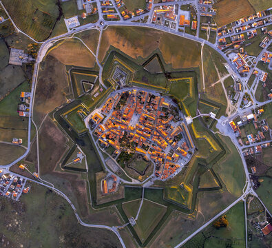 Aerial view of the historic star-shaped fortress of Almeida with dense terracotta rooftops, geometric defensive walls, and surrounding rural landscape in Almeida, Guarda District, Portugal.