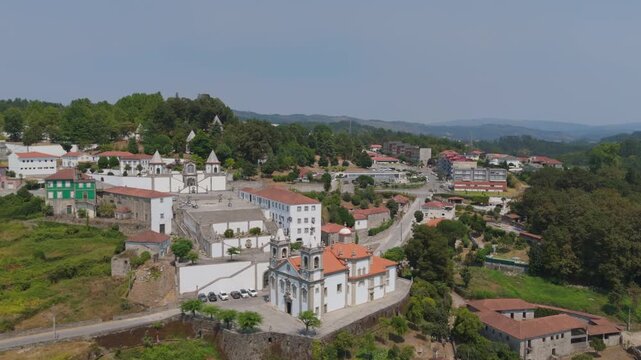 Aerial view of the Santuario de Nossa Senhora de Porto de Ave surrounded by lush greenery and historic buildings in Taide, Braga, Portugal.