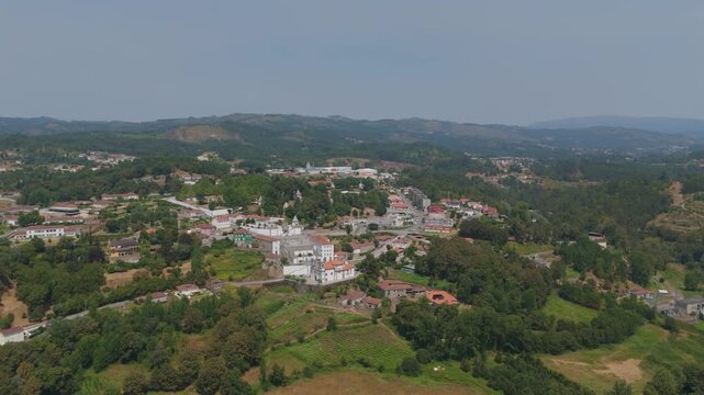 Aerial view of the Santuario de Nossa Senhora de Porto de Ave surrounded by lush green hills, trees, and the town of Taide, Braga, Portugal.