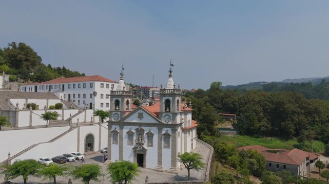 Aerial view of the Santuario de Nossa Senhora de Porto de Ave with its white facade and red-tiled roof surrounded by terraced gardens in Taide, Braga, Portugal.