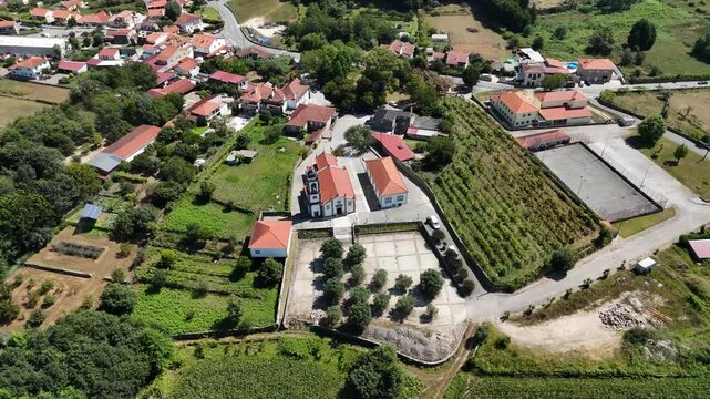 Aerial view of the Igreja Paroquial de Freixo surrounded by rural fields, vineyards, and traditional houses in Freixo, Viana do Castelo, Portugal.
