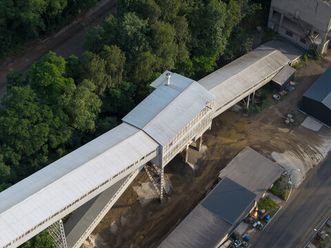 Aerial view of the stone mine conveyor belt structure surrounded by lush forest and an adjacent road in Zalas, Lesser Poland Voivode, Poland.