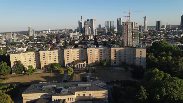 Aerial view of Goethe University Frankfurt with its historic stone building and surrounding parkland, set against the modern skyline of Frankfurt am Main, Hessen, Germany.