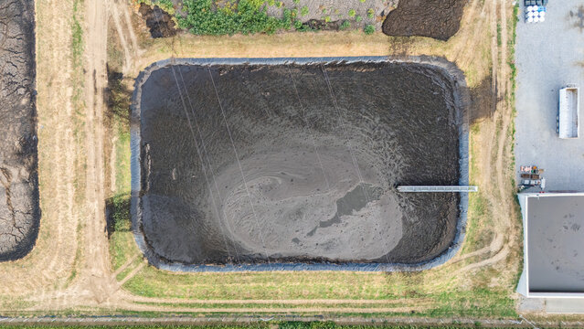 Aerial view of a wastewater treatment pond with dark liquid and a metal walkway in Serbia.