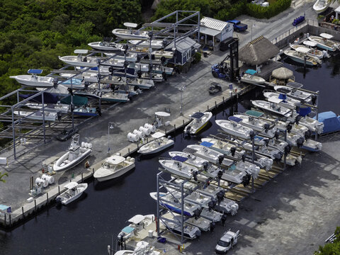 Islamorada, Florida, United States - 23 June 2026: Aerial view of the boat storage facility in Islamorada, featuring rows of stacked motorboats in metal racks and a forklift on the dock.
