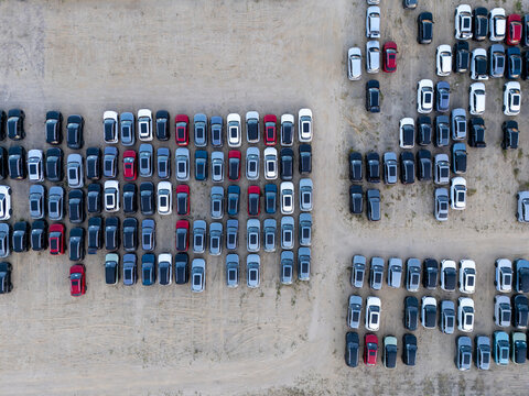 Aerial view of rows of parked cars in a storage lot with various colors and models arranged on a dirt surface in Gdansk, Pomeranian Voivodeship, Poland.