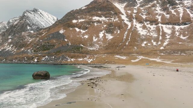 Aerial view of Haukland Beach with turquoise water and snow-dusted mountains in Leknes, Nordland, Norway.