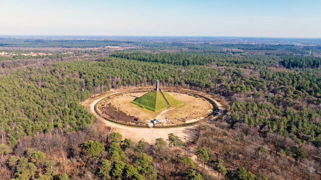 Aerial view of the Pyramid of Austerlitz, a historic monument surrounded by dense pine forests and circular paths in Woudenberg, Utrecht, Netherlands.