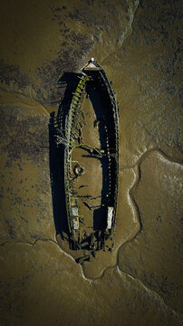 Aerial view of an abandoned wooden boat wreck resting in the mudflats of the boat cemetery in Lanester, Brittany, France.