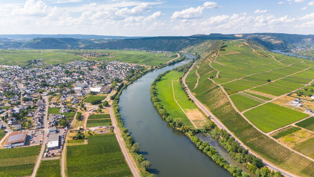 Leiwen, Germany - 15 July 2026: Aerial view of Leiwen village and the Moselle river loop surrounded by lush green vineyards under a bright blue sky.