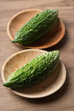 Fresh bitter gourd or bitter melon in a natural plate on a wooden background, Asian vegetables and herbal medicine