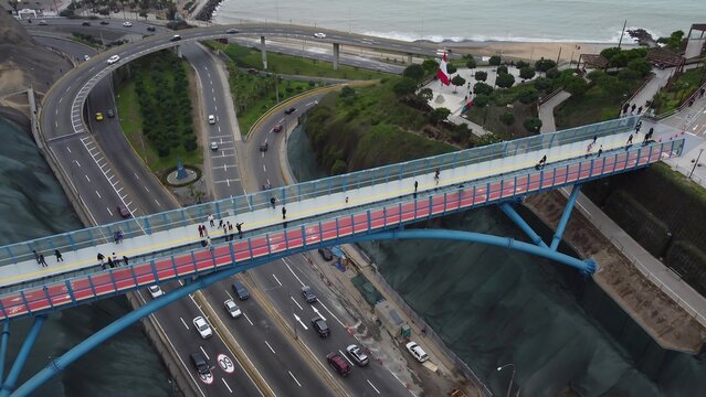 Aerial view of Puente de la Paz, a pedestrian bridge with a red path crossing over a busy highway in Miraflores, Provincia de Lima, Peru.