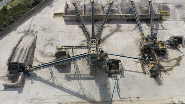 Aerial view of an industrial aggregate processing plant with conveyor belts and piles of gravel in La Longueville, Hauts-de-France, France.