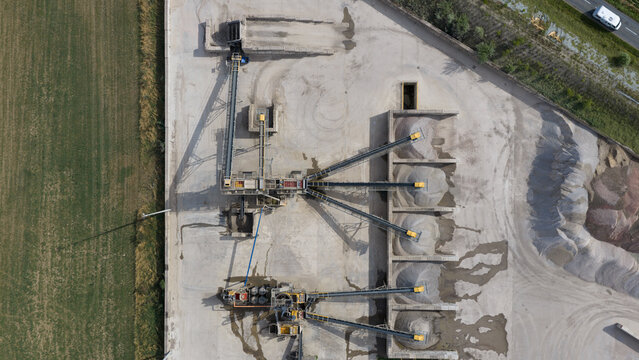 Aerial view of a gravel and sand processing plant featuring conveyor belts, sorting machinery, and piles of aggregate in La Longueville, Hauts-de-France, France.