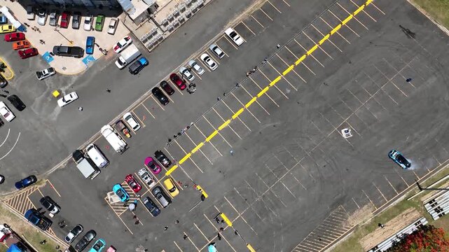 Aerial view of the parking lot at Coliseo Municipal Maestro Tomas Dones Hernandez with parked cars and people in Fajardo, Fajardo, Puerto Rico.