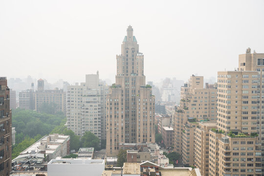 New York, United States - 16 July 2026: View of a prominent Art Deco skyscraper rising above the surrounding residential buildings in Manhattan under a hazy sky.