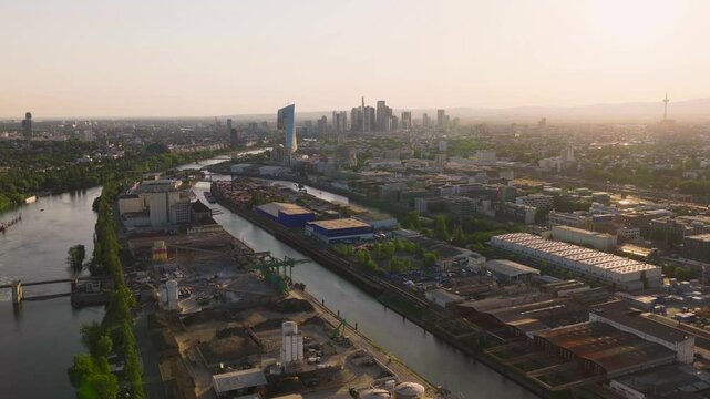 Aerial view of Osthafen industrial area along the Main river with the Frankfurt skyline in the background at sunset in Frankfurt am Main, Hessen, Germany.