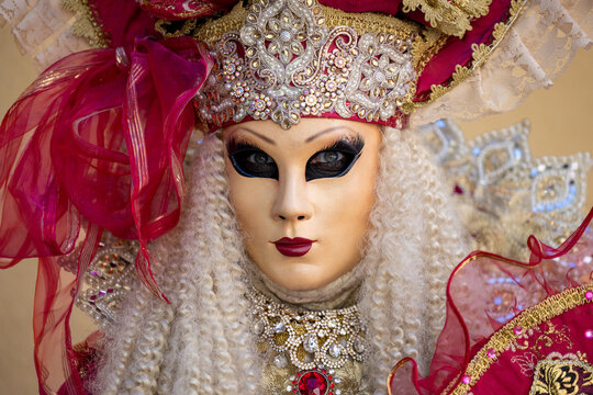 Riquewihr, France - 04 July 2026: View of a person wearing an elaborate Venetian-style mask and ornate red and gold costume with intricate lace and jewels.